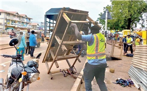 A member of the Tamale Municipal Assembly task force trying to carry a hawker’s table away